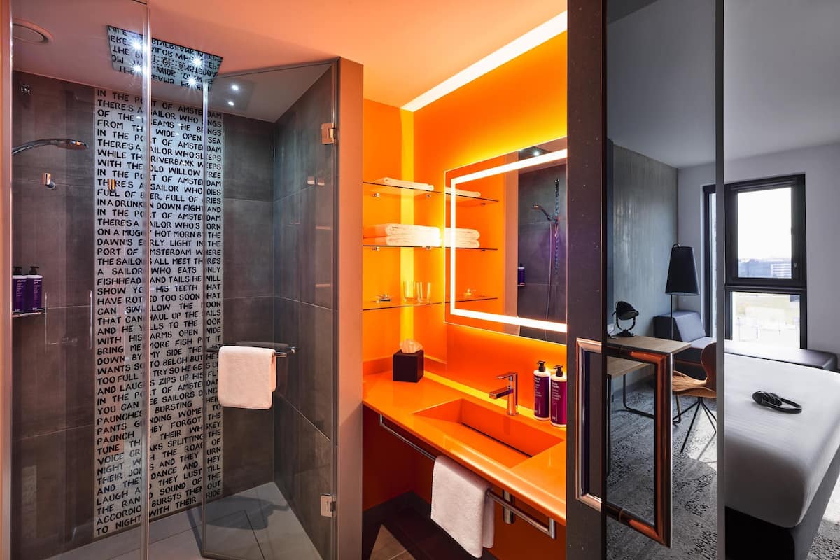 A modern bathroom with a glass shower enclosure, a sink with a mirror, and a towel rack.