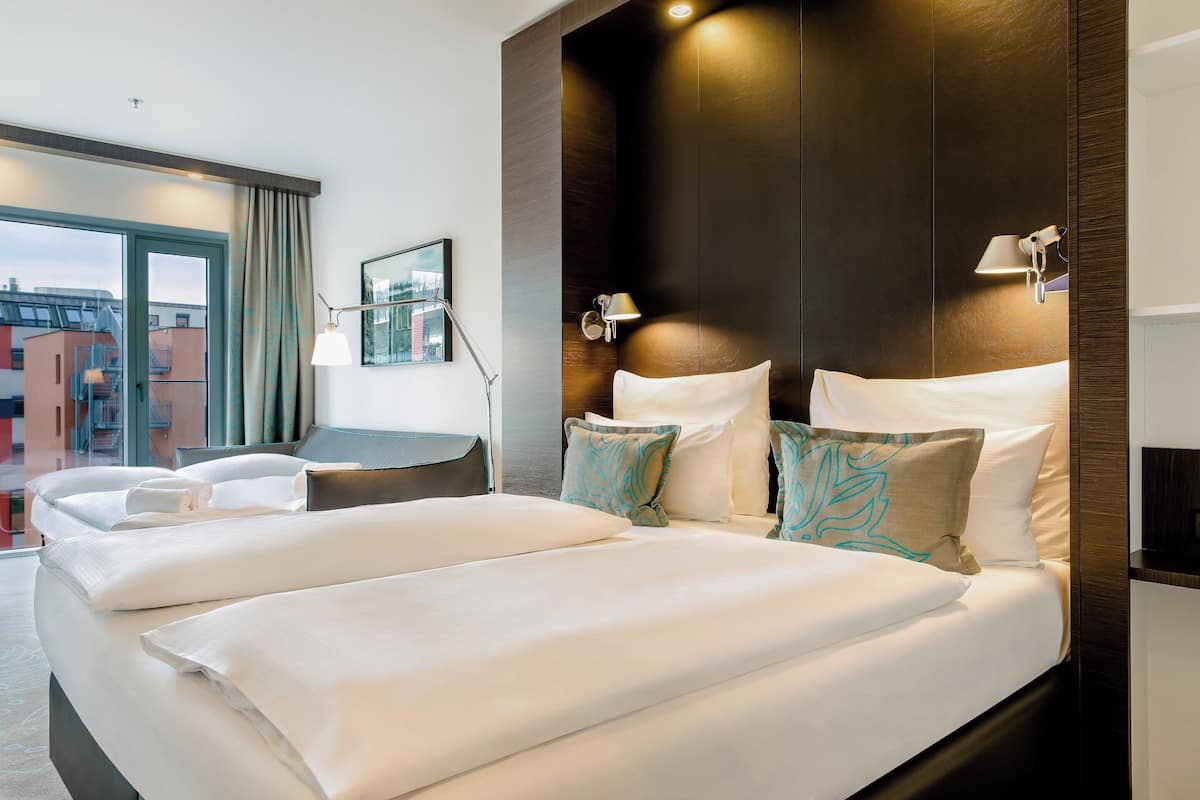 A hotel room with a large bed, a desk, and a view of the city.