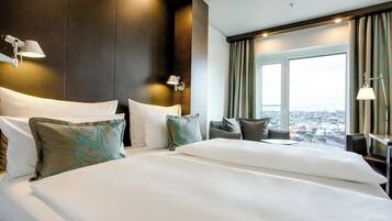 A hotel room with a large bed, two bedside tables, a desk, and a window with a city view.
