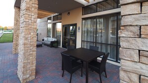 Un patio al aire libre con piso de ladrillo, una pérgola de madera y una mesa con sillas.