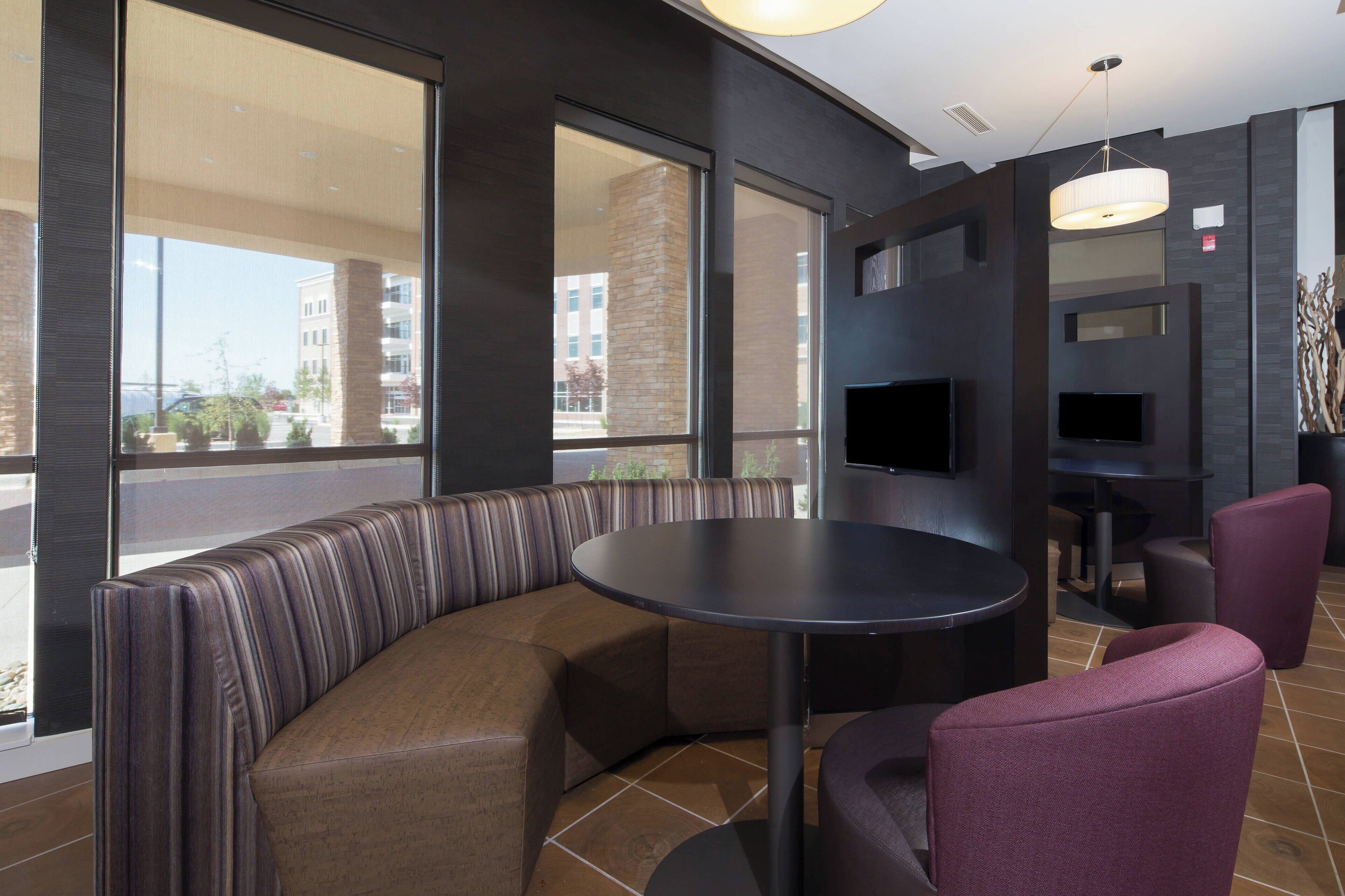 A modern interior with a curved seating area, a round table, and a flat-screen TV mounted on the wall.