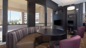 A modern interior with a curved seating area, a round table, and a flat-screen TV mounted on the wall.