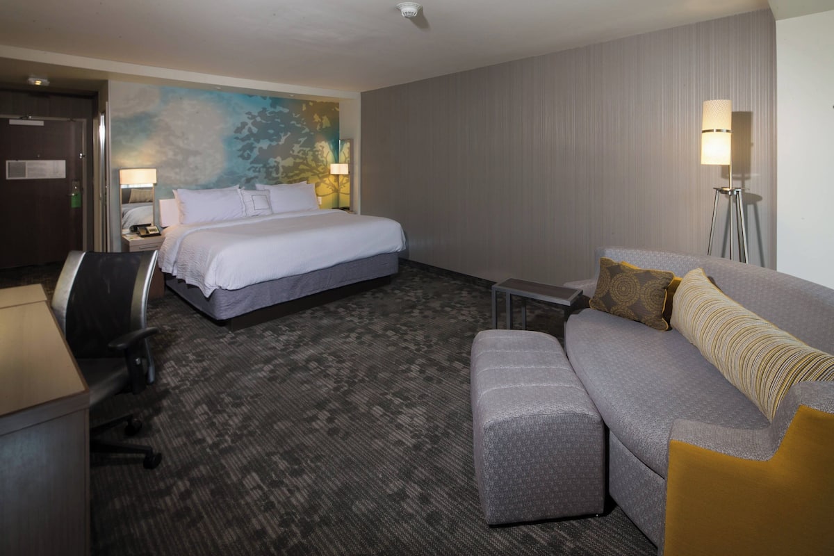 Ein Hotelzimmer mit Bett, einer Couch, einem Schreibtisch und einem Stuhl.
