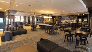 Un moderno vestíbulo de hotel con áreas de descanso, un bar y una recepción.
