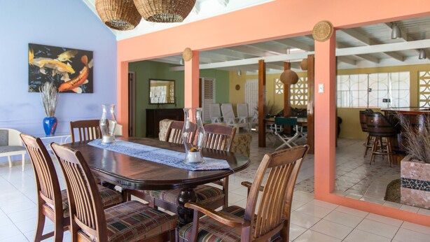 A dining area with a large wooden table, multiple chairs, and hanging wicker lamps. - Gemini Villa (Montego Bay)
