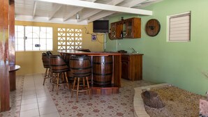 A kitchen with a bar area, wooden stools, and a tiled floor. - Gemini Villa (Montego Bay)