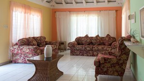 A living room with two floral-patterned sofas, a small table, and a wicker coffee table. - Gemini Villa (Montego Bay)