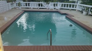 A rectangular pool with a tiled edge and a metal ladder leading into it. - Gemini Villa (Montego Bay)