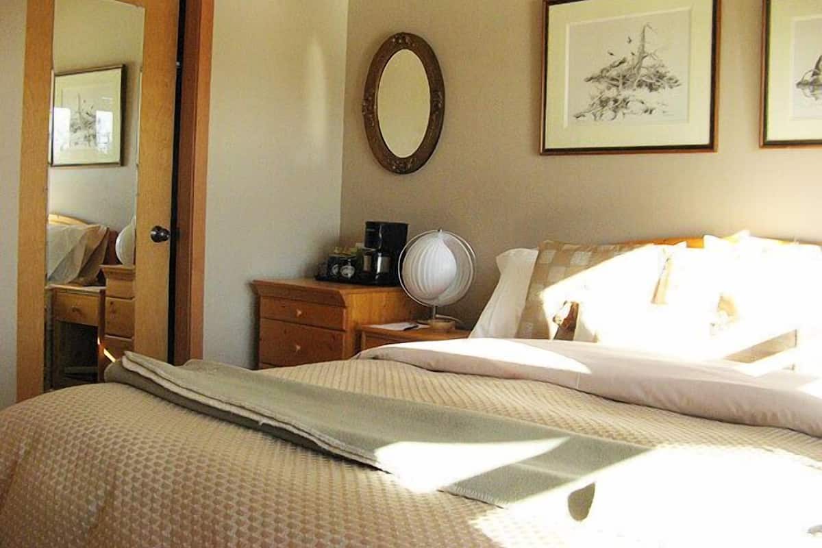Un dormitorio con cama, cómoda, espejo y dos cuadros en la pared.
