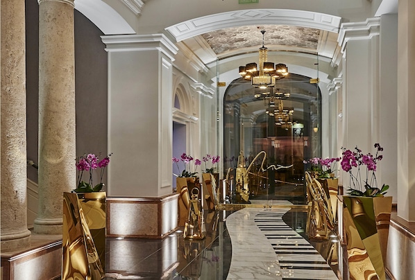 A luxurious hallway with marble floors, gold accents, and potted orchids. - Aria Hotel Budapest by Library Hotel Collection (Budapest)