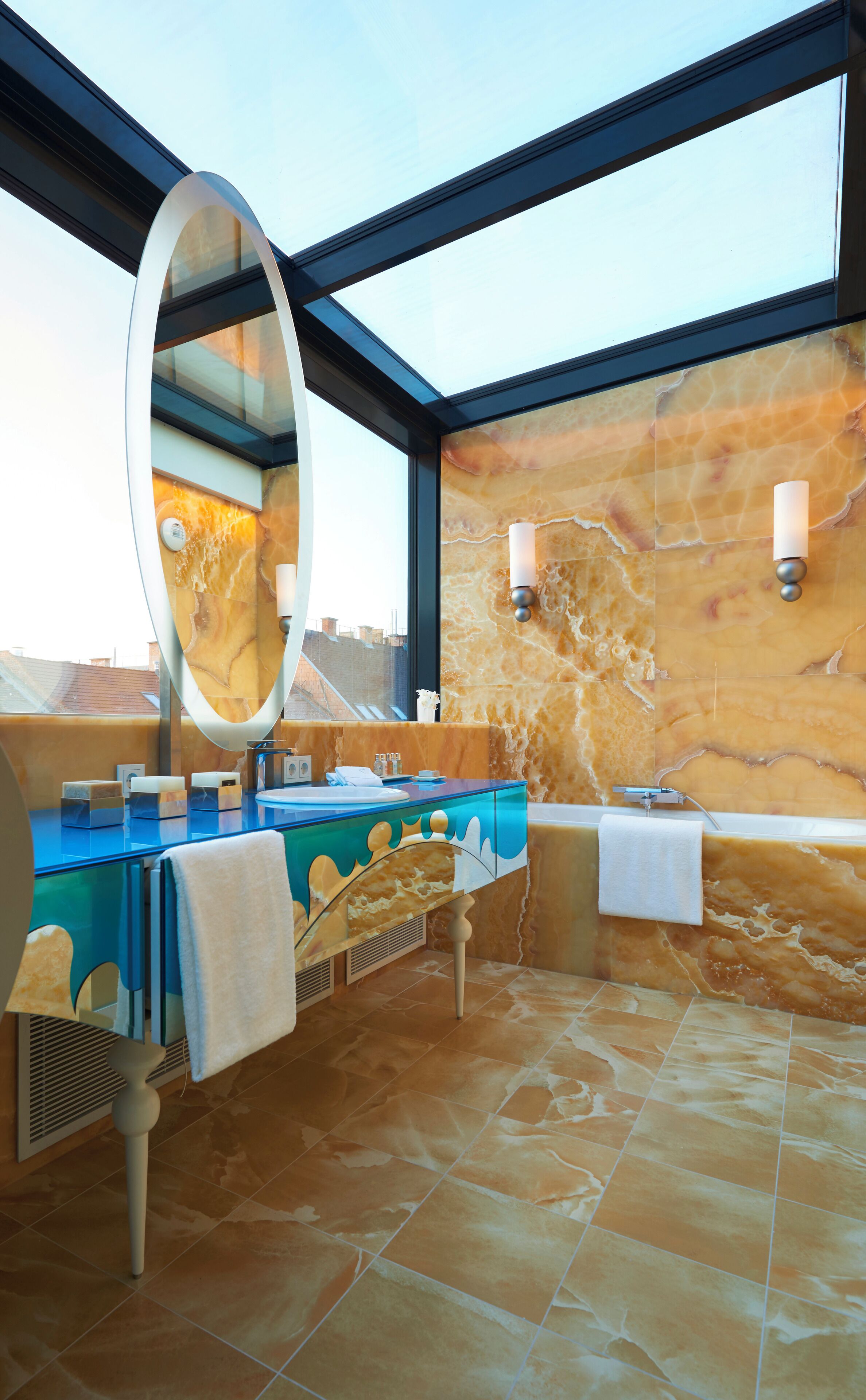 A modern bathroom with a glass-enclosed shower, marble walls, and a large mirror.