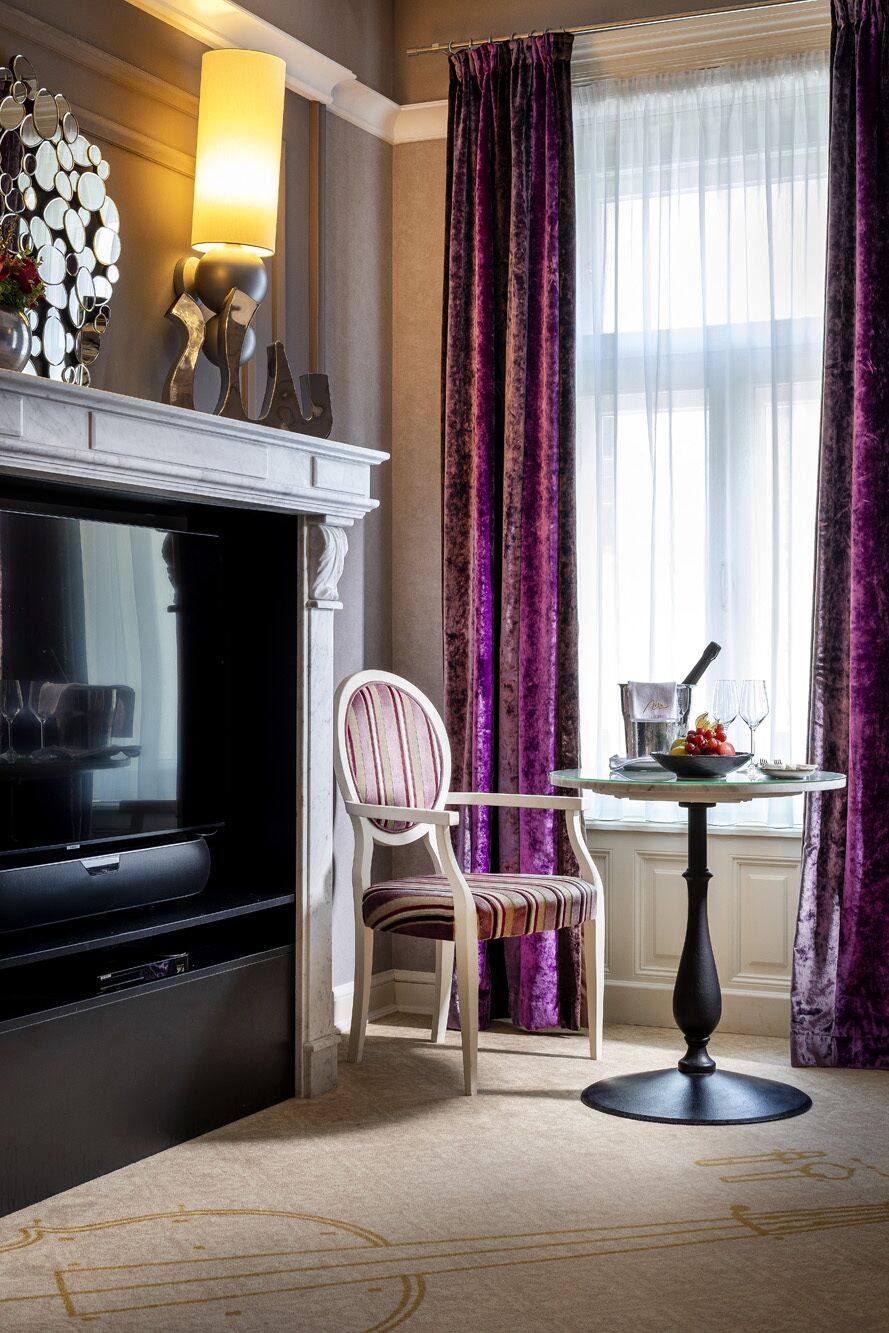 Une pièce avec une cheminée, un téléviseur, une table à manger avec un saladier de fruits et une chaise.
