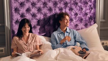 Een koppel zit op een bed met een gestoffeerd hoofdbord, terwijl ze een tijdschrift lezen.