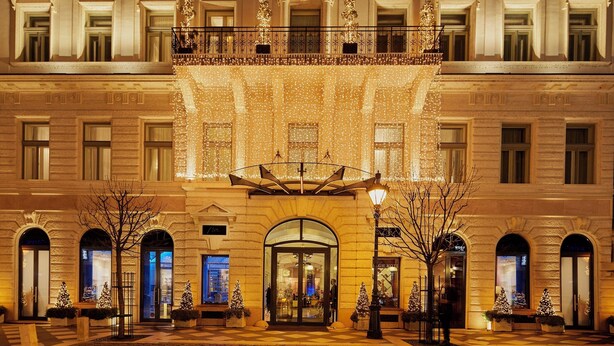 Une imposante façade ornée d’arcades et d’une entrée centrale, décorée de guirlandes lumineuses et d’arbres de Noël.