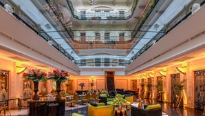 Un hall d’entrée spacieux avec un atrium central, de nombreux espaces de détente et un piano.