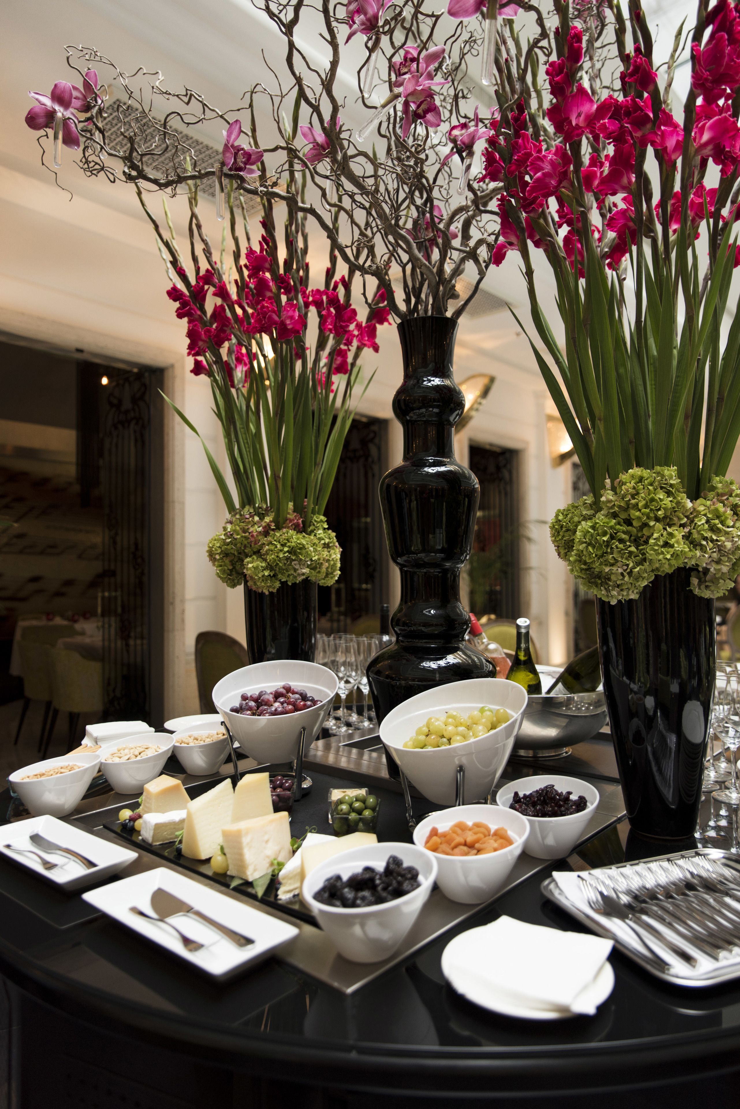 Taula de buffet amb diversos plats i vasses decoratives plenes de flors.