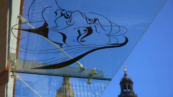 A glass window with a decorative design, a metal bracket, and a reflection of a building's dome.