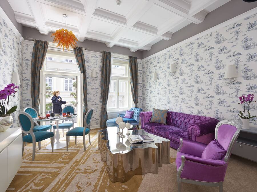 A spacious living room with a large sofa, a coffee table, and a dining area with chairs and a table.