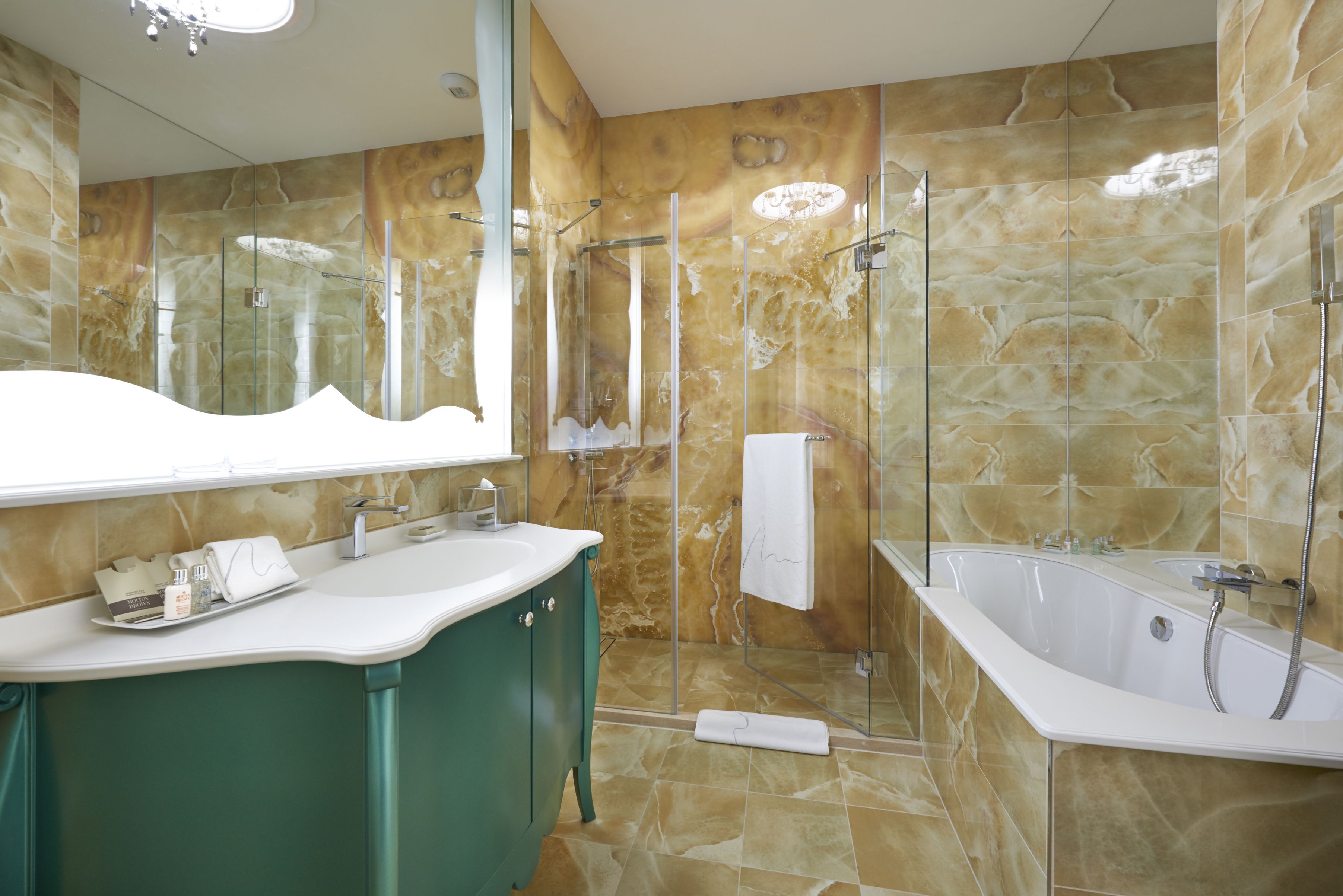 A modern bathroom with a large mirror, a freestanding bathtub, and a glass-enclosed shower.