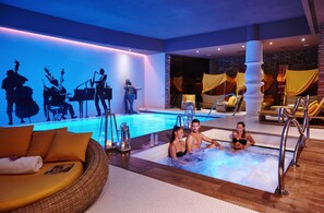 A hotel pool area with a hot tub, lounge chairs, and a mural on the wall.