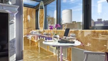 Una habitación de hotel moderna con un tragaluz grande, suelo de baldosas de mármol, comedor con mesa y sillas, y vistas a la ciudad.
