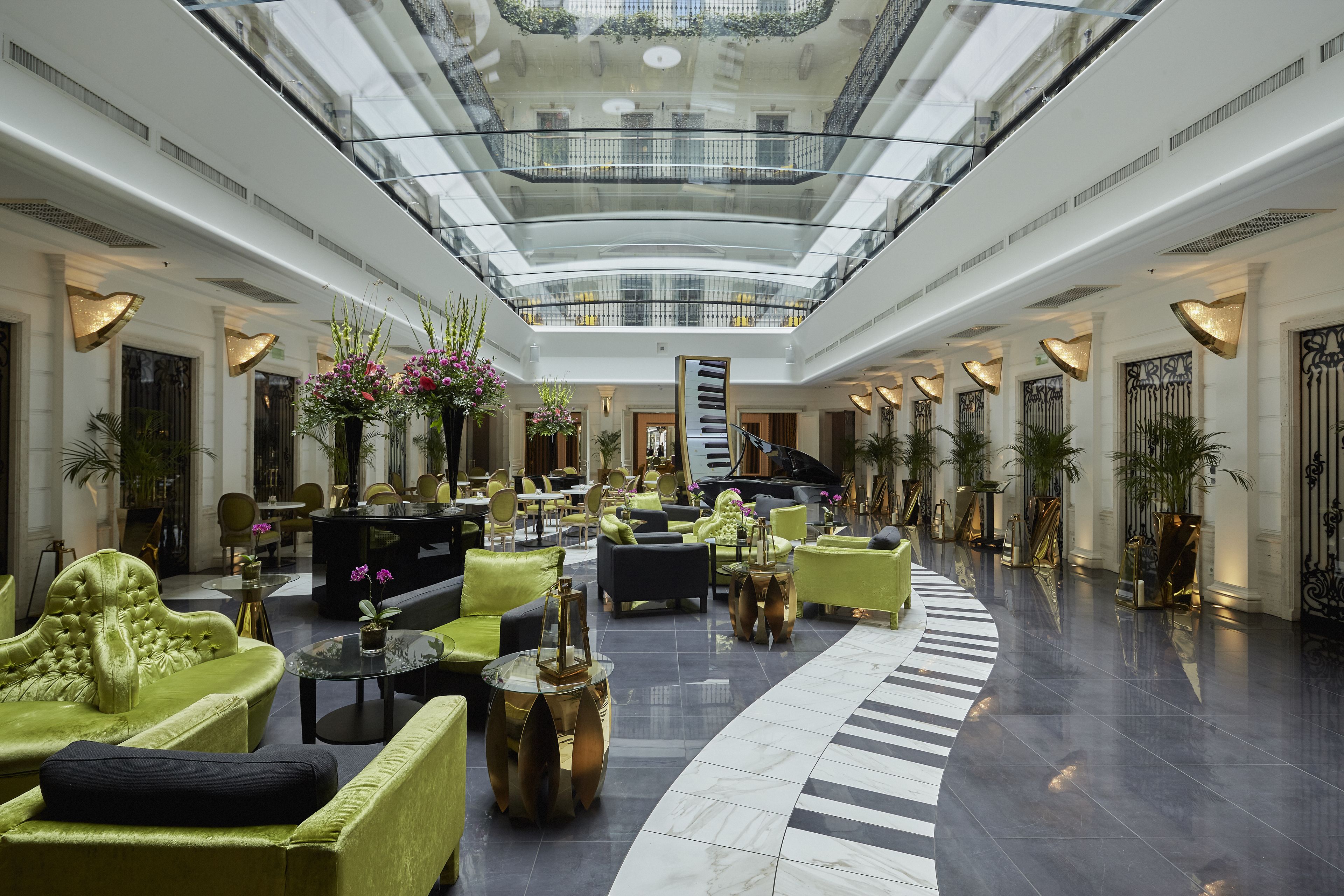 A spacious lobby with a high ceiling, multiple seating areas, and a central staircase.