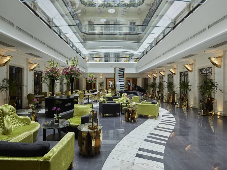 A spacious lobby with a high ceiling, multiple seating areas, and a central staircase.