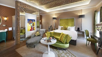 Habitación de hotel con una cama grande, un sofá, una mesa de comedor y un baño con espejo y lavamanos.