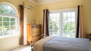A bedroom with a bed, a dresser, and a window with curtains.