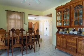 A dining area with a wooden table and chairs, a cabinet with glass doors, and a tiled floor.
