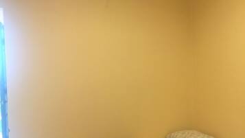 A room with a bed, a pillow, a blanket, and an air conditioning unit on the wall.