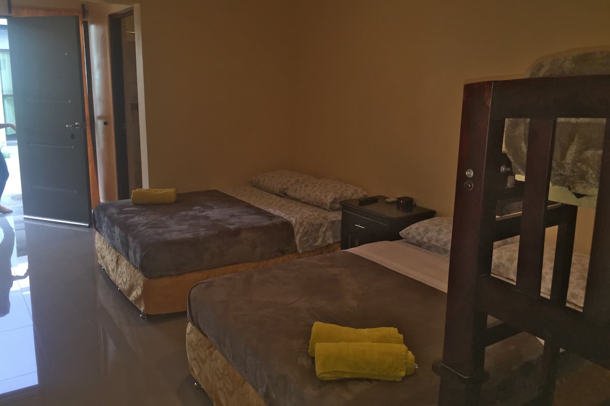 Una habitación con dos camas, una mesita de noche y una silla.