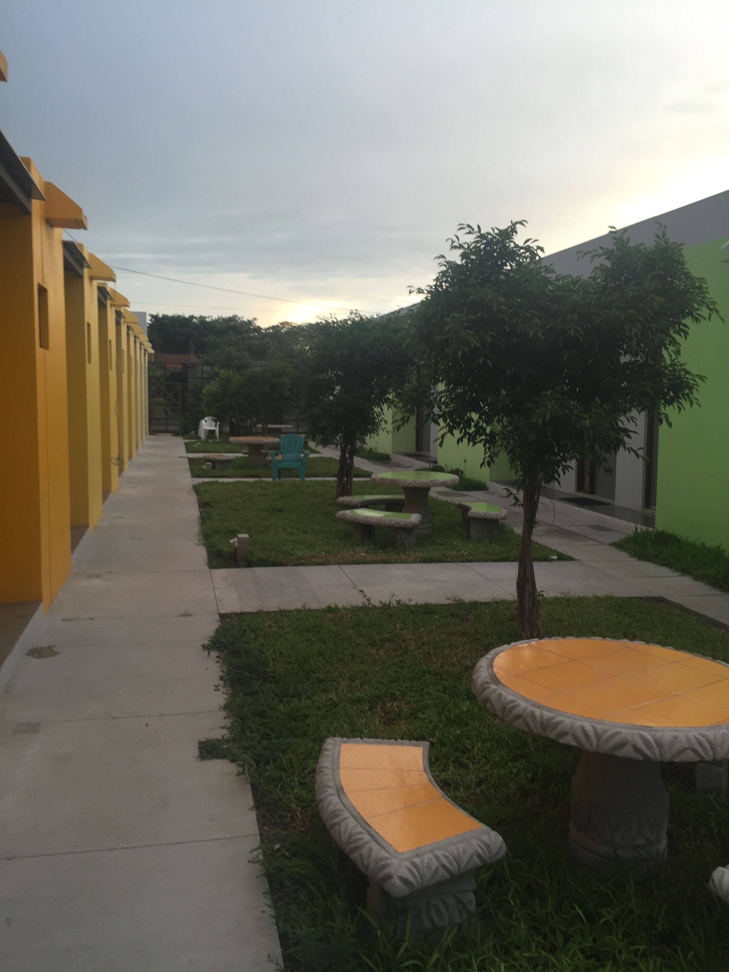 Un patio con un edificio amarillo, paredes verdes y zonas de estar al aire libre.