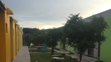 Un patio con un edificio amarillo, paredes verdes y zonas de estar al aire libre.