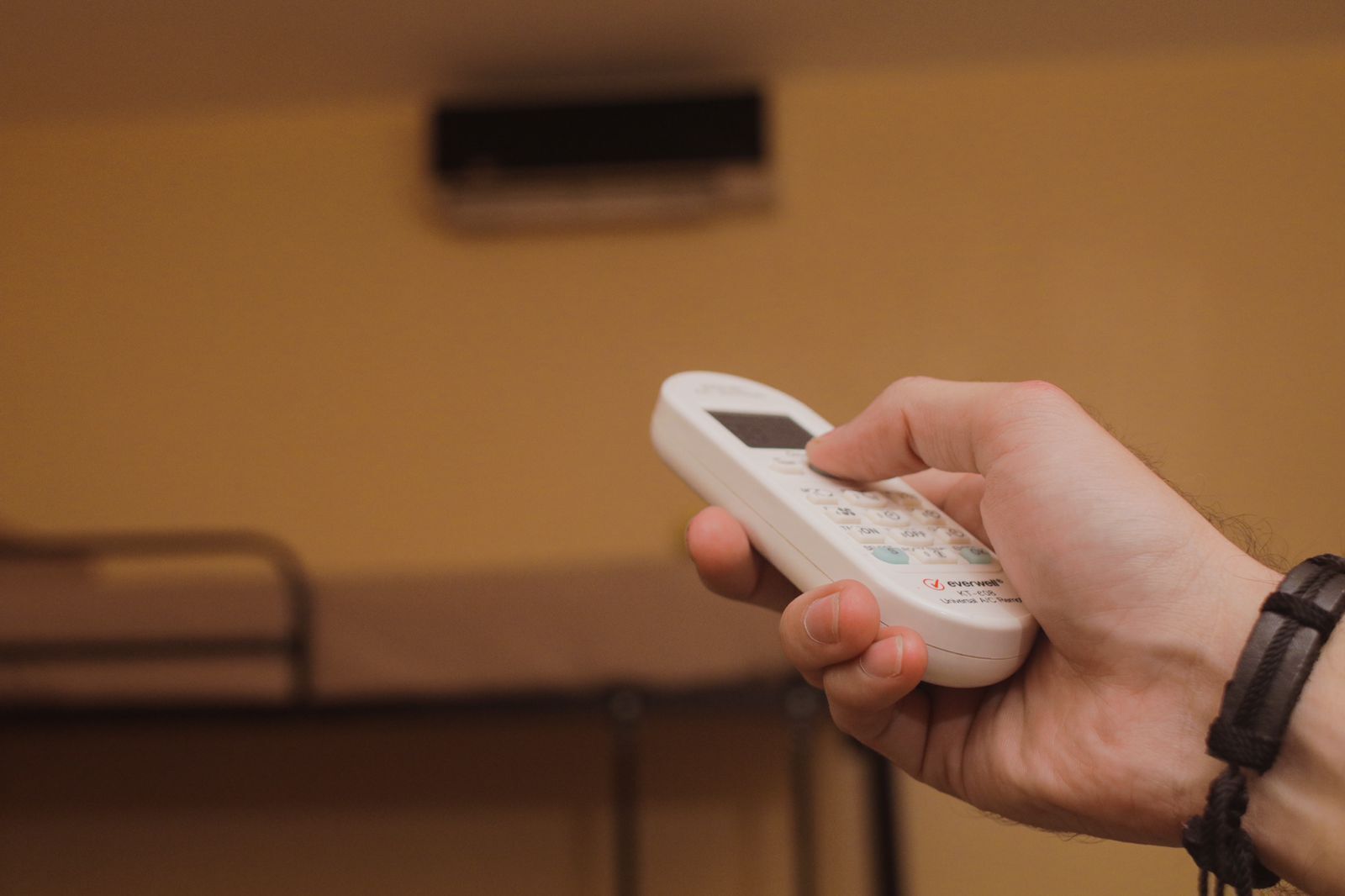 Uma mão segura um telemóvel branco com teclado e ecrã pequeno, à frente de uma parede lisa com uma ventilação.