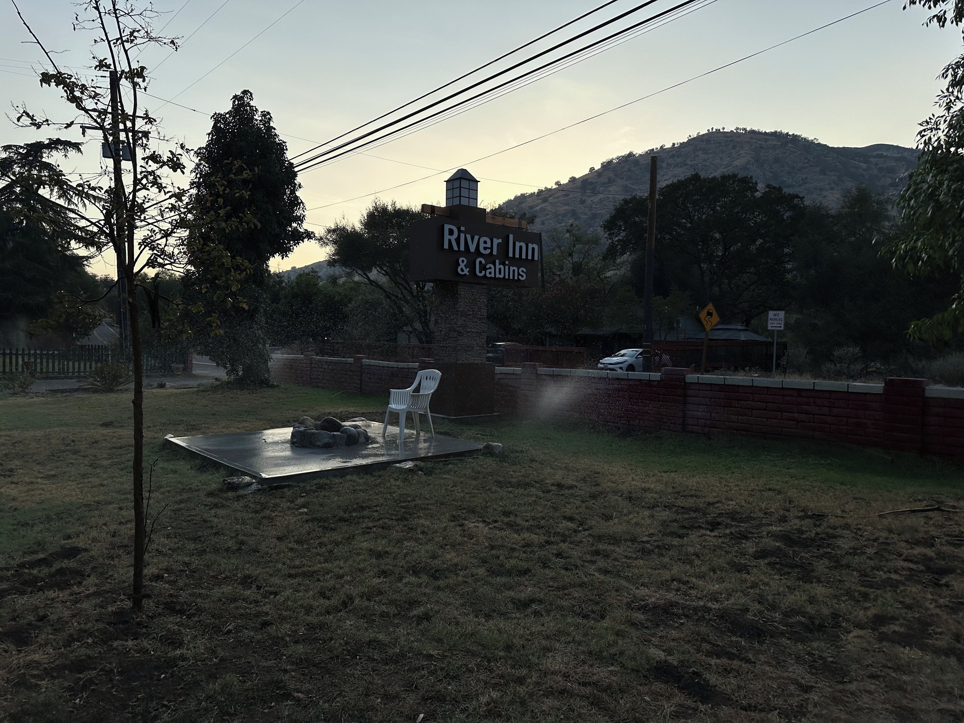 A sign for River Inn & Cabins with a view of a hilly landscape in the background.