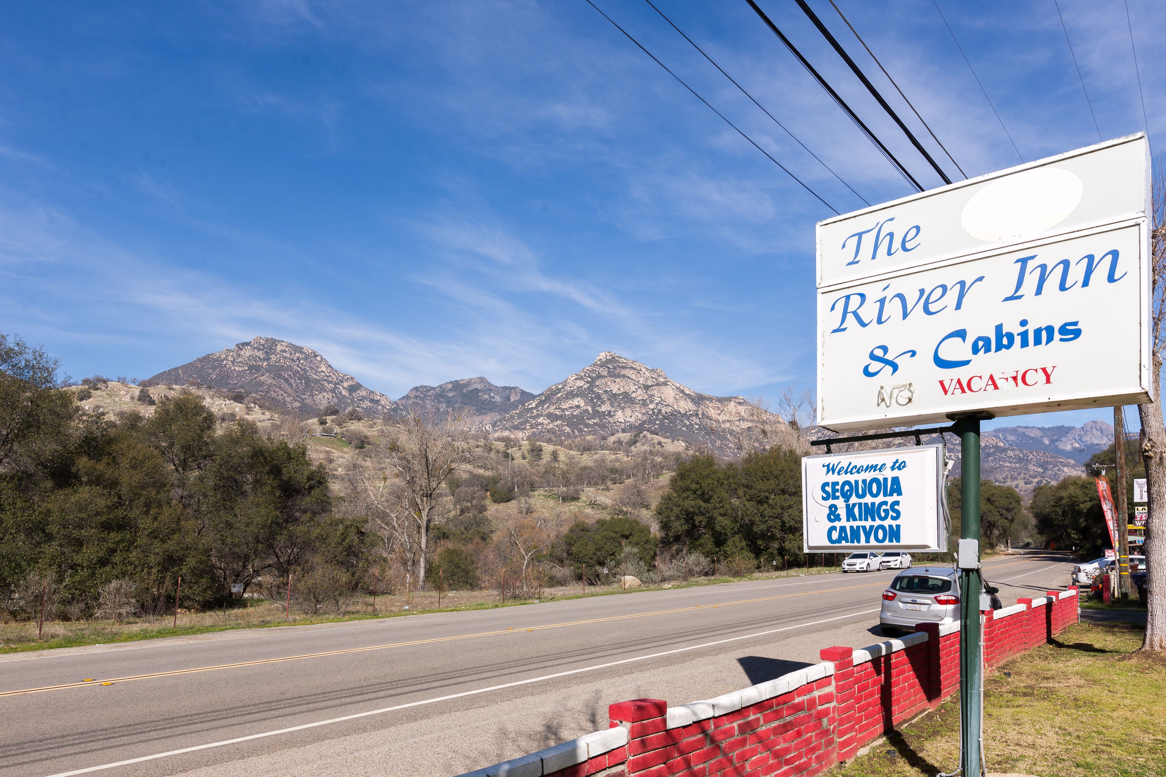 A road sign for The River Inn & Cabins with a view of mountains in the background.