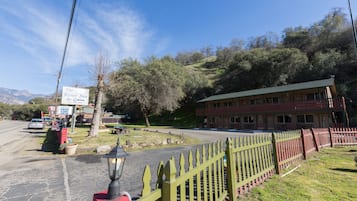 A two-story building with a green roof, a red picket fence, and a sign for The River Inn & Cabins.