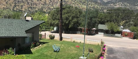 A residential street with houses, a grassy lawn, and a wooden fence.