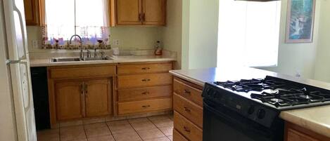 A kitchen with wooden cabinets, a stove, and a sink.