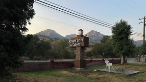 A sign for River Inn & Cabins with a mountainous backdrop. - The River Inn (Three Rivers)