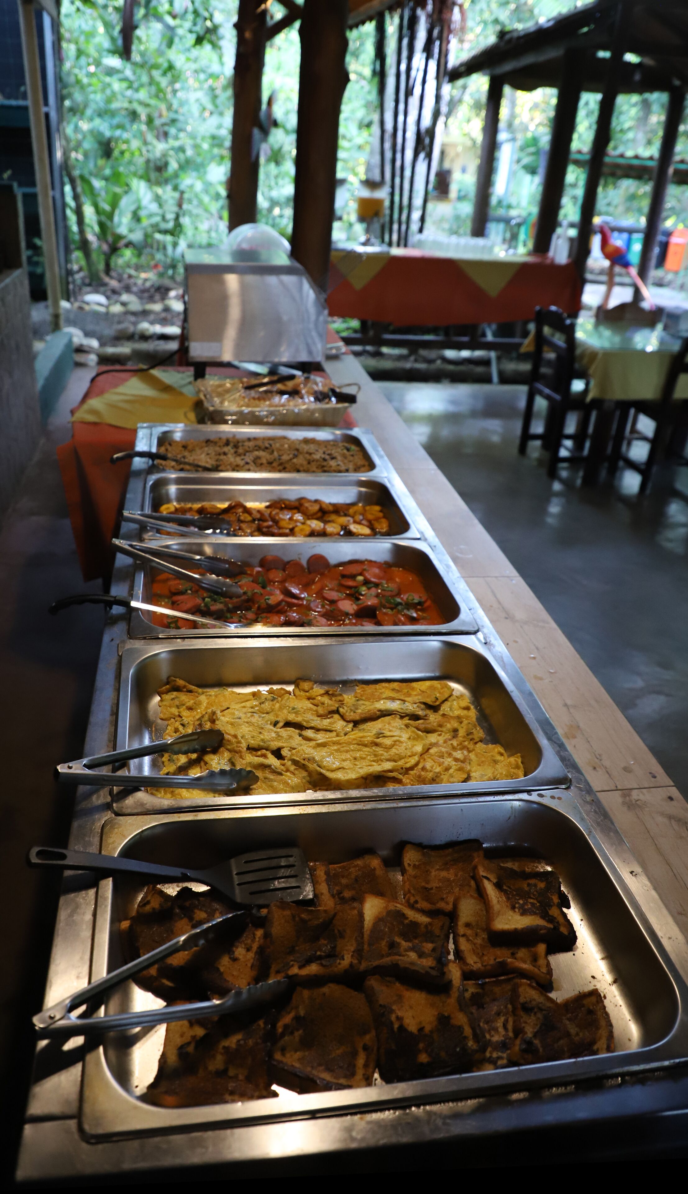 A buffet line with various food items and serving utensils.
