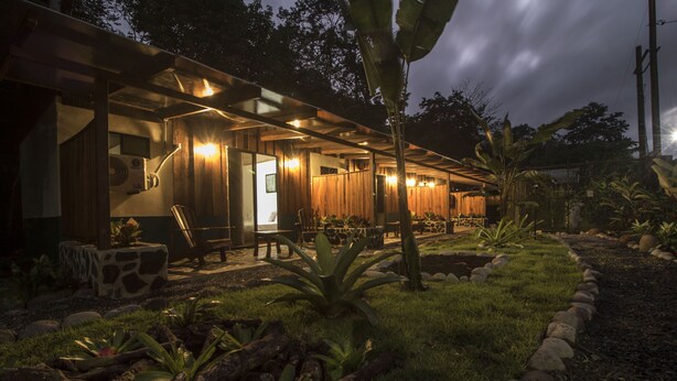 Un espace de détente extérieur moderne, doté de structures en bois, de sièges et de plantes tropicales.