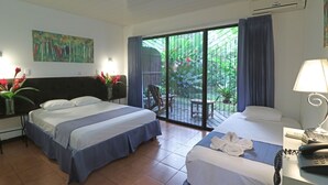 Une chambre d’hôtel avec deux lits, un balcon donnant sur un espace verdoyant, un tableau au mur et un téléphone sur la table de chevet.