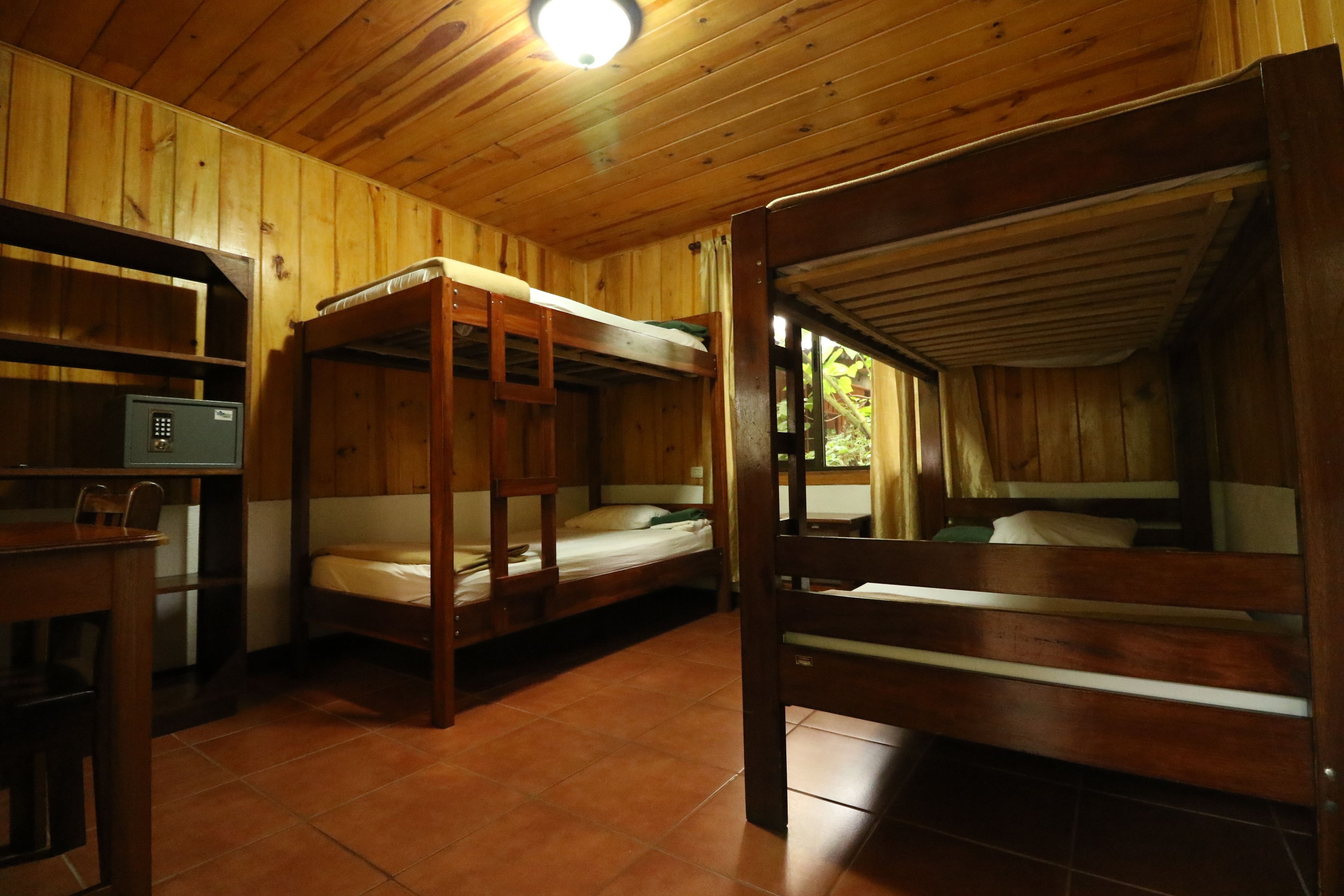 Una cabaña de madera con literas, un escritorio y una caja fuerte.