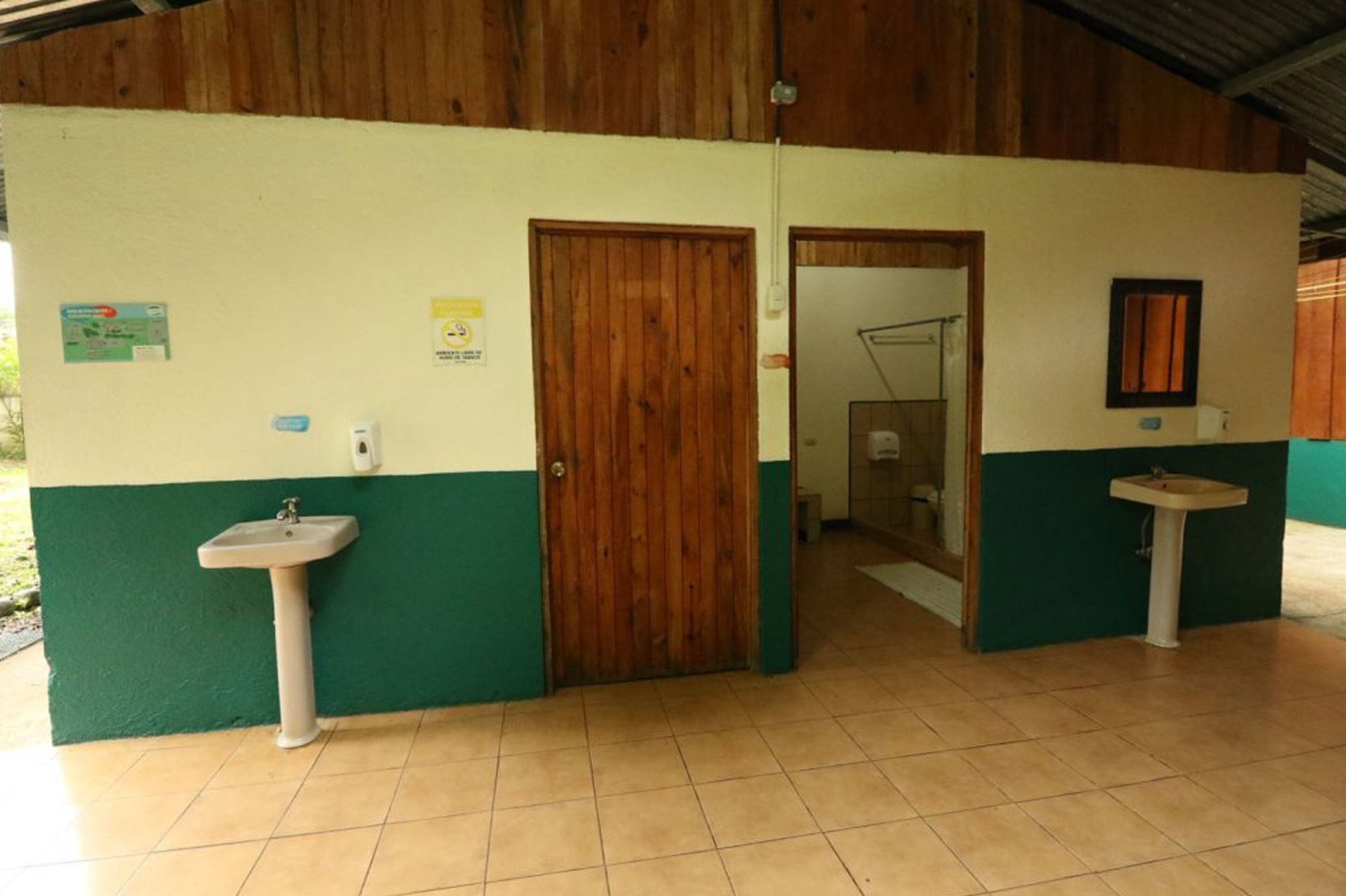 Un baño con dos lavamanos, puertas de madera y suelo de baldosas.