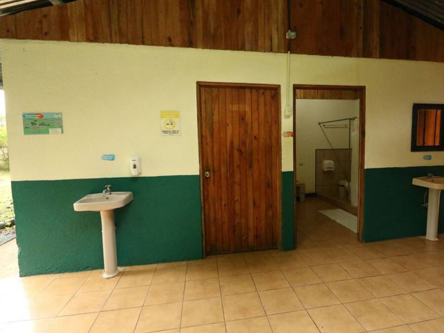 Un baño con dos lavamanos, puertas de madera y suelo de baldosas.