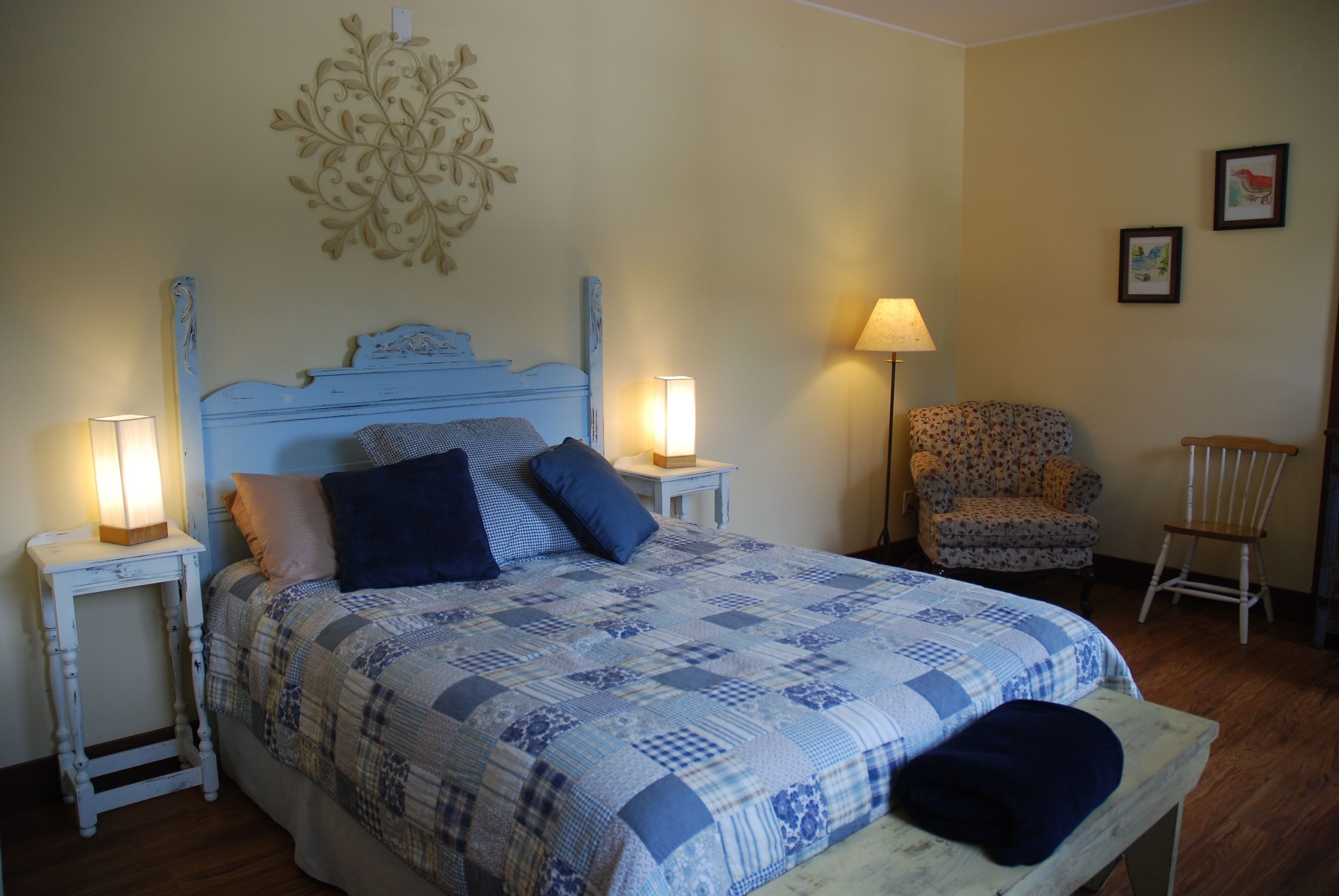 Une chambre à coucher comprenant un lit, deux tables de chevet avec des lampes, une chaise et un élément décoratif mural.