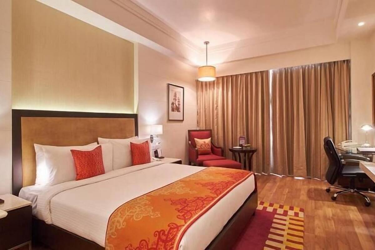 Ein Hotelzimmer mit Bett, Schreibtisch, Stuhl und Vorhängen.