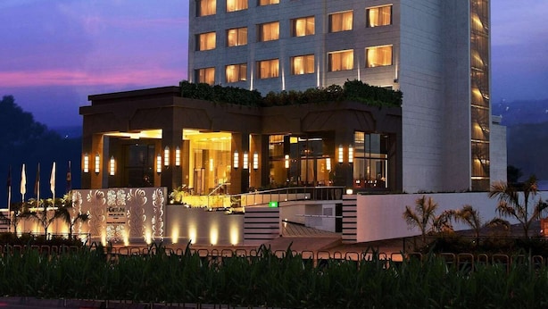 Een meerlaags hotel met een opvallend 'FORTUNE' bord, met een moderne gevel en verlichte ramen.